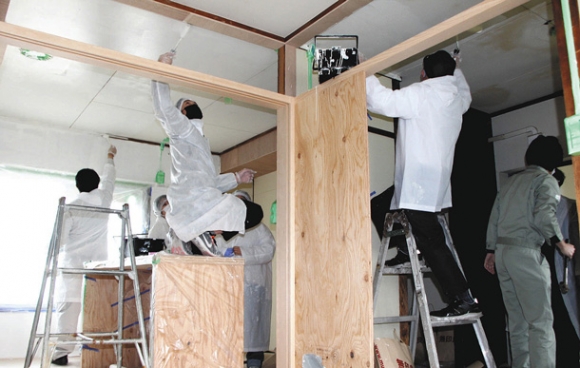 協力して天井や壁にペンキを塗る学生と住民＝四日市市あさけが丘３で