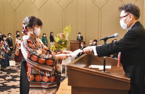 丸山学長(右)から学位記を受け取る卒業生代表者=四日市市安島の都ホテル四日市で