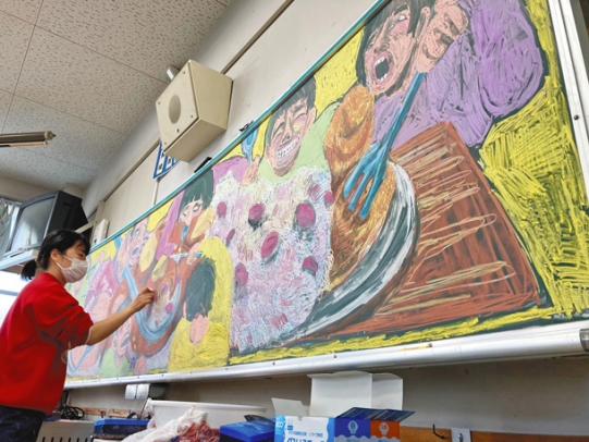 黒板にチョークでにぎやかな給食風景を描く宮原さん＝名古屋市東区の東桜小で