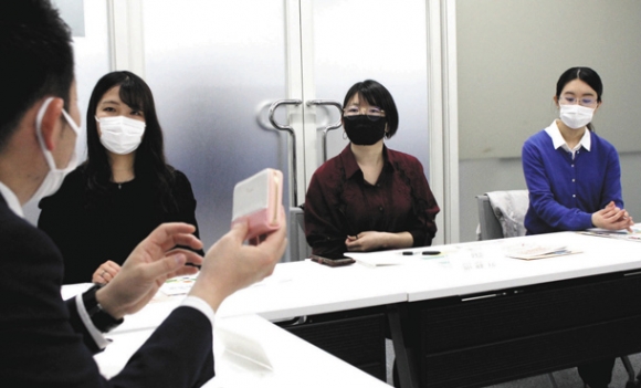 防犯ブザーについて説明する署員（左）の話を聞く学生たち＝守山区の金城学院大で