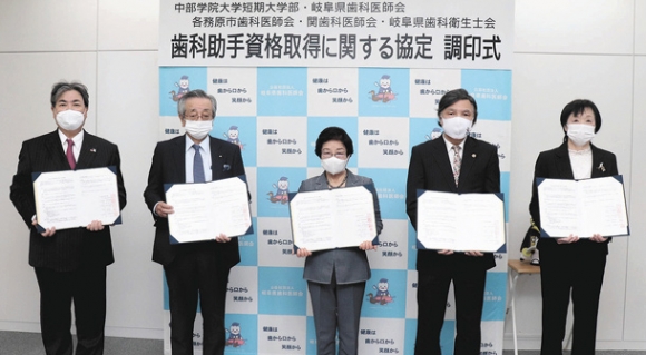 協定書を交わした片桐学長（中）ら＝岐阜市の県歯科医師会館で