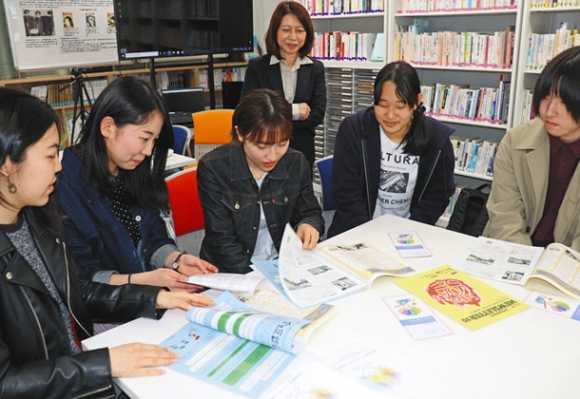 編集に携わったニュースレターを見ながら、ジェンダーについて話し合う学生と坂田所長(後方)=いずれも長久手市の愛知淑徳大「ジェンダー・女性学研究所」で