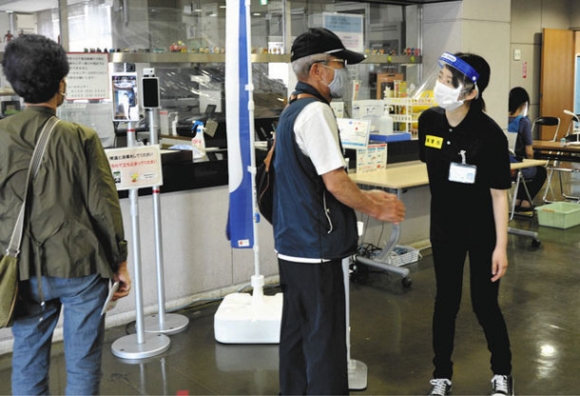 集団接種に訪れた高齢者を案内する実習生（右）＝大府市保健センターで