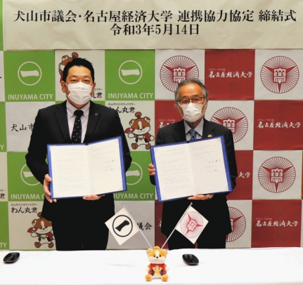 協定書を持つ（左から）中村市議、佐分学長＝犬山市役所内の議場で