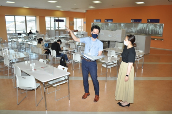 接種会場となる学生食堂で打ち合わせをする市職員（手前左）と大学職員＝愛知県東海市の星城大で
