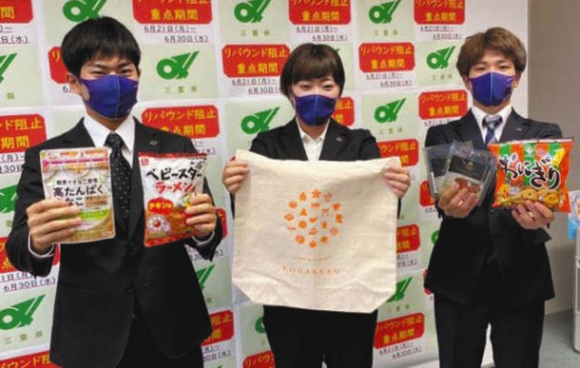 県内の企業などから提供を受けた商品を手にする皇学館大生ら＝県庁で（まごころお届け三重プロジェクト提供）