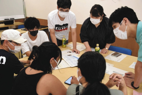 外国籍住民らの接種予約を手伝う学生たち（奥）＝知立市もやいこハウスで