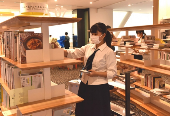 本棚に本を並べる高校生＝豊橋市駅前大通のまちなか図書館で