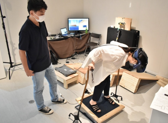 体を少し傾けただけでも落下する感覚に陥るＶＲ体験装置で楽しむ来場者＝東区大幸南１の市民ギャラリー矢田で