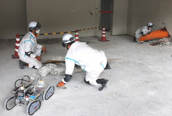 ロボットが安全を確認した後、担架を運びこむ隊員＝豊田市藤岡飯野町で