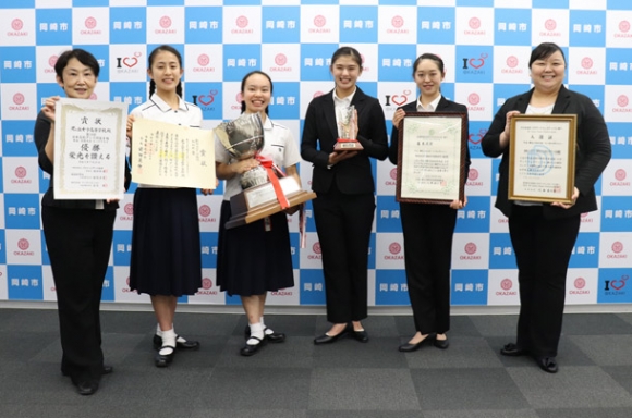入賞した光ケ丘女子高と岡崎女子大・短期大のダンス部員や顧問ら＝岡崎市役所で
