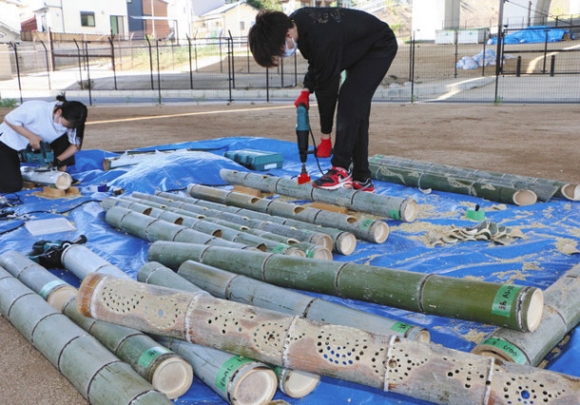 電動ドリルなどで竹に穴を開ける学生＝緑区有松で