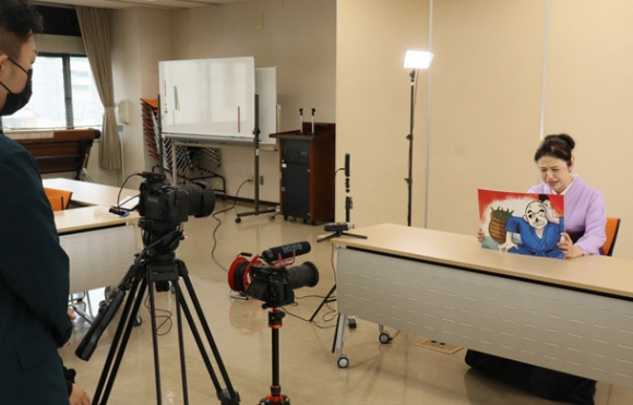 旭堂鱗林さん（右）の読み聞かせの様子を撮影する学生ら＝瀬戸市役所で