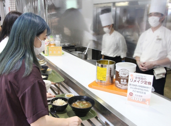 非常食をアレンジしたメニューを注文する学生(左)=四日市市萱生町で