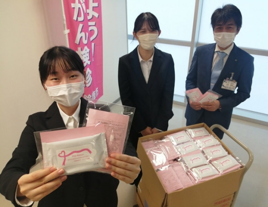 オリジナルデザインの除菌シートパックを中村部長に手渡した稲葉さん（左）と種市さん（中）＝鈴鹿市役所で