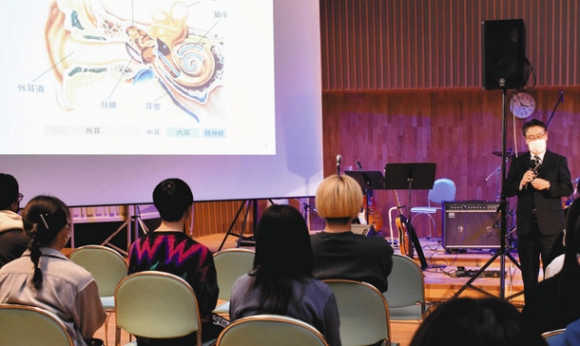 耳栓も活用しながら耳を守るよう訴える今井さん（右）＝北名古屋市の名古屋芸術大で