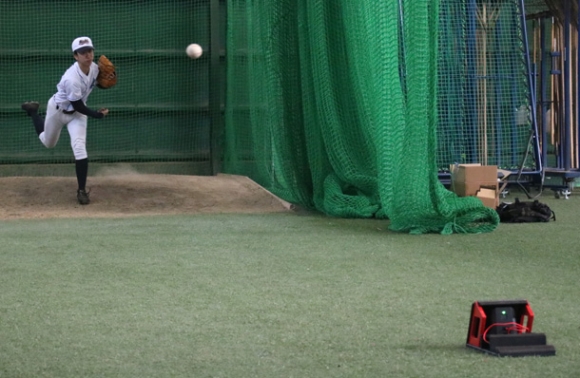 ラプソードを前に、投球する部員＝愛知大豊橋キャンパスで