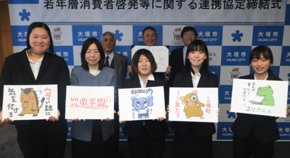消費者啓発のイラストを手にするプロジェクトメンバーの学生ら＝大垣市役所で