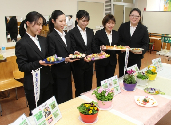 鉢植えの食用花やハーブを使って作った料理を手にする学生たち=各務原市那加桐野町の東海学院大で