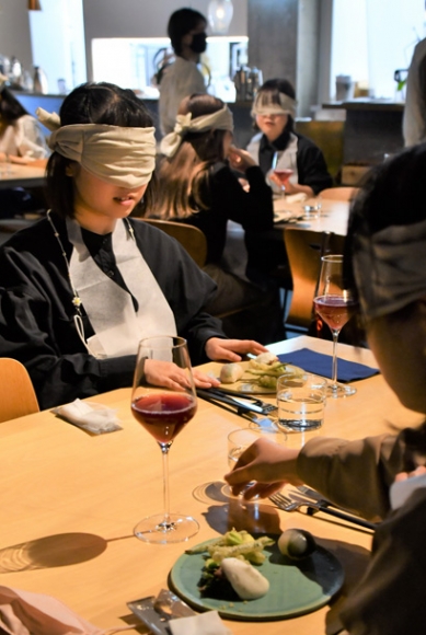 目隠しをして手探りで料理を楽しむ「ブラインド・レストラン」の参加者ら＝千種区星が丘元町で