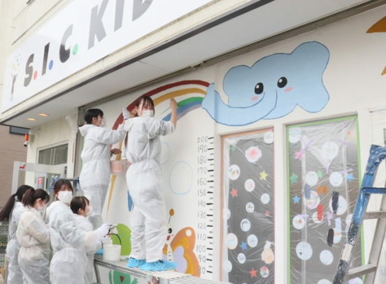 入り口付近の壁にゾウなどの絵を描く学生＝尾張旭市三郷町で