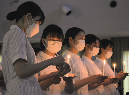 ろうそくの火をともす学生ら＝関市桐ケ丘の中部学院大で