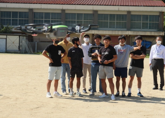 ドローンの飛行体験をする学生＝尾張旭市平子町の平子の森で