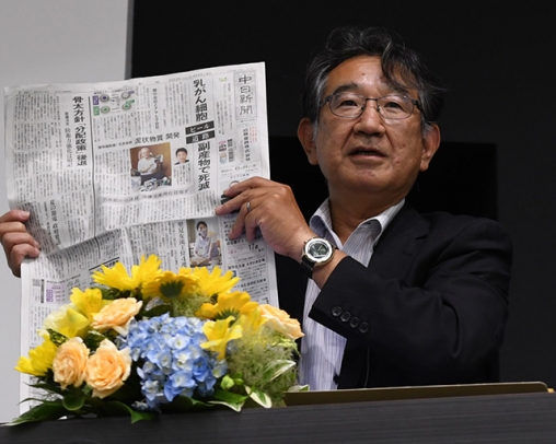 中日新聞を手にしながら講演する寺本局長＝瑞穂市穂積の朝日大で