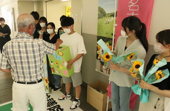 ヒマワリの花を配りながら募金を集める学生たち＝尾張旭市の名鉄瀬戸線尾張旭駅で