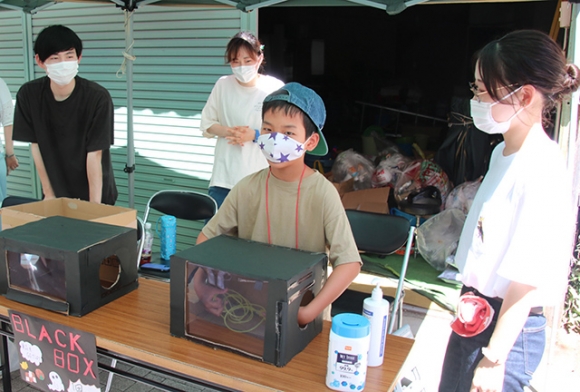 箱の中身を触って当てるゲームに挑戦する子どもら＝豊橋市花園町で