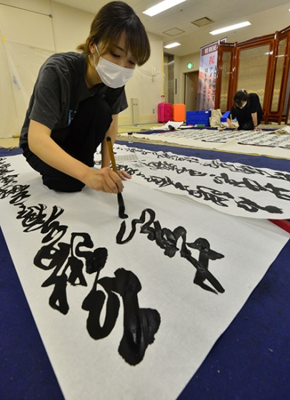 力強く書に臨む岐阜女子大の学生たち＝高山市の光ミュージアムで