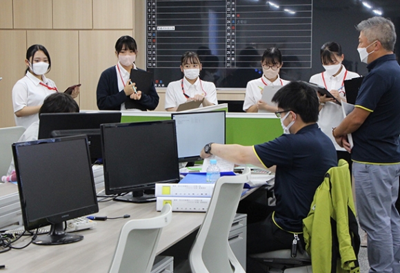 伊藤部長(右)の案内で社内を見学する学生たち=四日市市あかつき台の中村組で