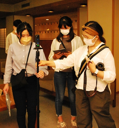水明館の館内で撮影の準備をする林講師（右）と学生＝下呂市で