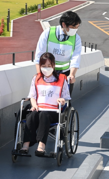 医療避難所に車いすで移動する患者役の職員ら＝豊明市の藤田医科大で