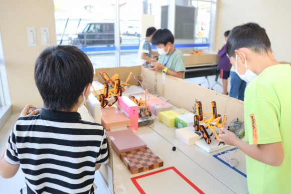 空き箱で作ったコースでロボットを走行させる子どもたち＝瀬戸市蔵所町の瀬戸蔵で