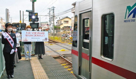大森・金城学院前駅を出発する列車を見送る１日駅長の戸崎さん（左）と広告研究会のメンバーたち＝守山区の同駅で