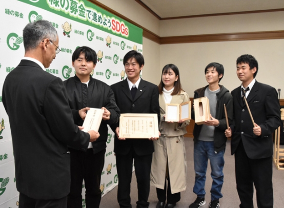 製作した商品を手に赤井専務理事（左）に寄付金を渡す名古屋聾学校の生徒と名城大の学生＝県三の丸庁舎で