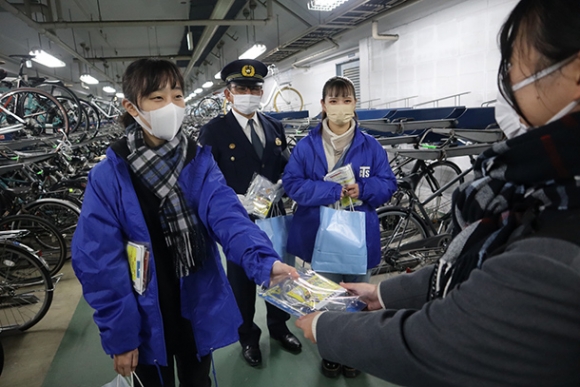 自転車の鍵かけを呼びかけるチラシなどを配る学生ら＝豊橋市の豊橋駅で