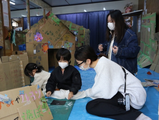 子どもたちのお絵描きを手伝う学生たち=北区の柳原通商店街で