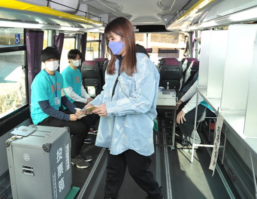 県知事選の期日前投票をする吉田さん（右）＝大府市横根町の至学館大で