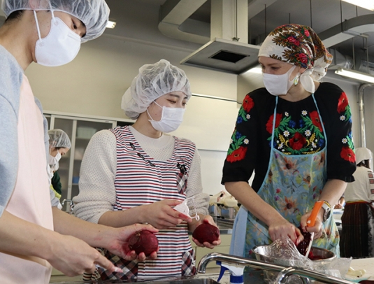 学生らと一緒にボルシチを作るオーリャさん（右）＝鈴鹿市の鈴鹿医療科学大で