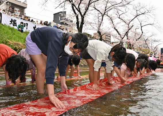 黒川友禅流しでのり落としを体験する子どもたち=北区の黒川で