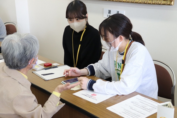 スマホの使い方を教える大学生ら=武豊町立図書館で