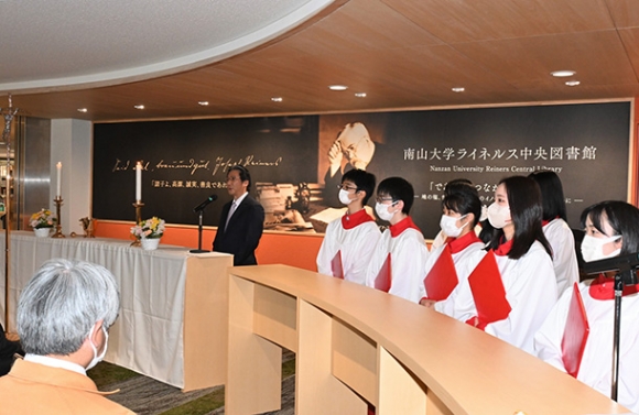 エントランスに新たに設けられたカウンターの前であいさつする太田図書館長(左奥)=昭和区の南山大で