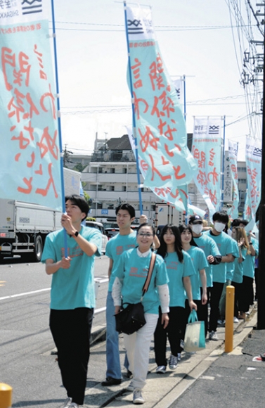 のぼり旗を持って投票を呼びかける越智准教授と学生たち＝大府市の至学館大周辺で