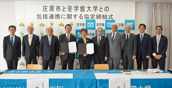 中央で協定書を持つ木山市長と谷岡学長と関係者たち＝大府市横根町の至学館大で