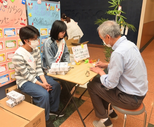 七夕の短冊にメッセージを書き込む献血協力者(右)=白山市幸明町で