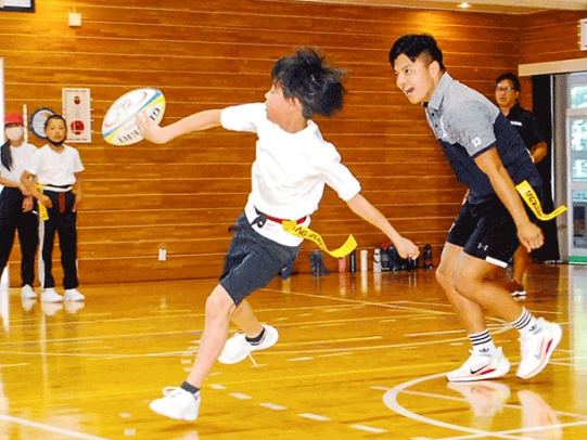 学生（右）を振り切り味方にパスをする児童＝下呂市で