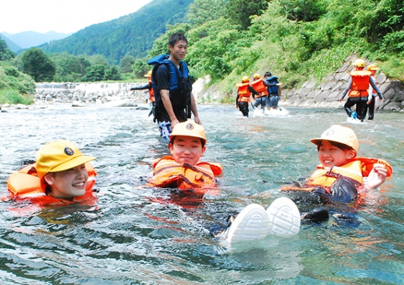 服の上にライフジャケットを着けて泳ぐ児童ら=下呂市で