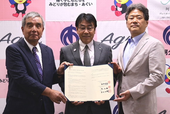 協定書を手にする田中町長（中）と日本福祉大の丸山理事長（左）、原田学長＝阿久比町役場で